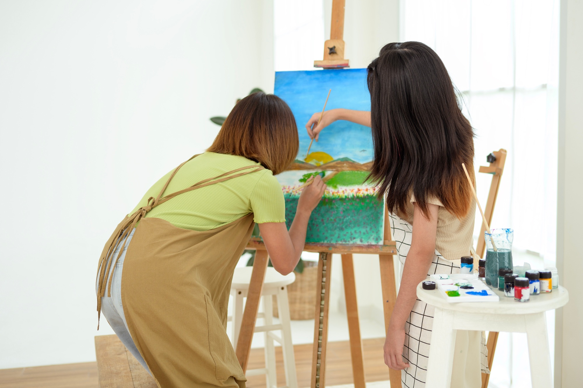 Two young Artists Creating Beautiful Landscape Paintings in a Bright Studio